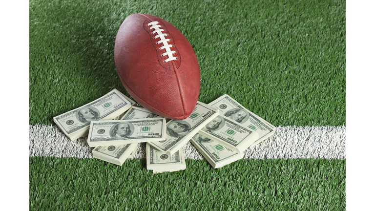NFL football sitting with piles of dollars on AstroTurf