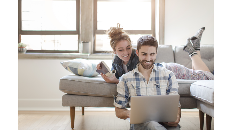 Young couple relaxing at home, looking at laptop