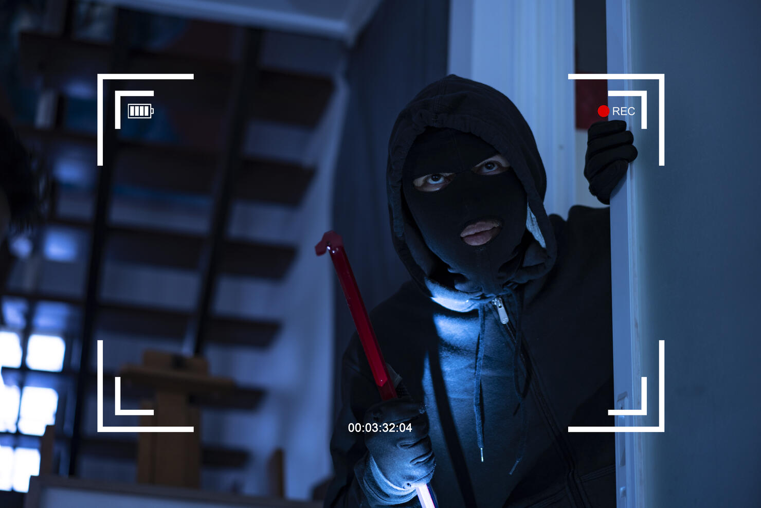 CCTV view of burglar breaking in to home through window with crowbar