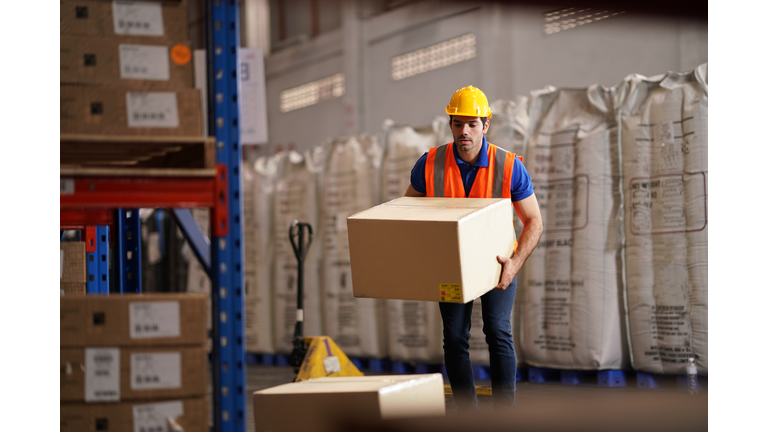 Warehouse worker carry merchandise box to pallet truck at storage compartment