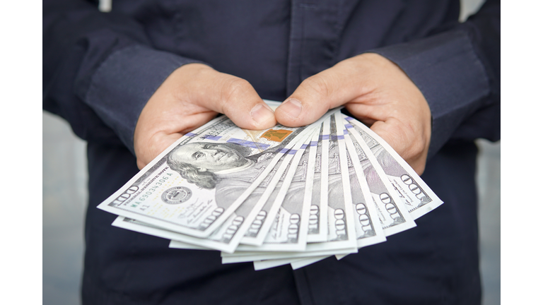 male hands with wrist watch is considered American dollars. Hands holding dollar cash. 1000 dollars in 100 bills in a man hand close-up on a dark background. hundred