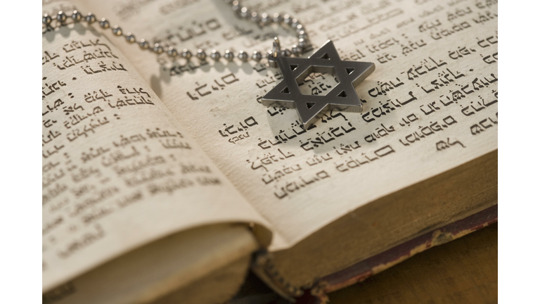 Star of David necklace on book with Hebrew text