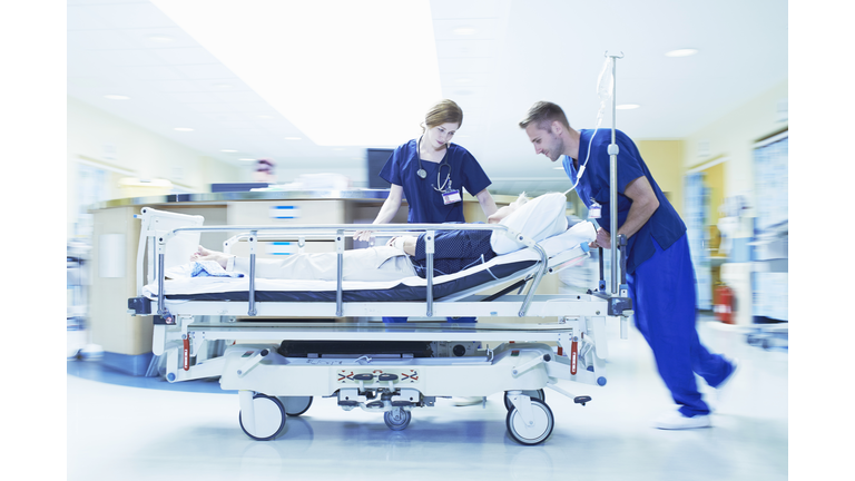 Two medics pushing gurney in hospital emergency room