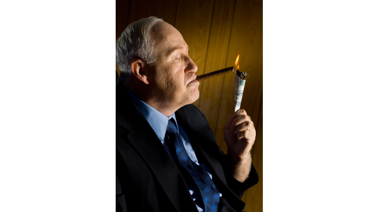 Man lighting cigar with 100 Dollar Bill