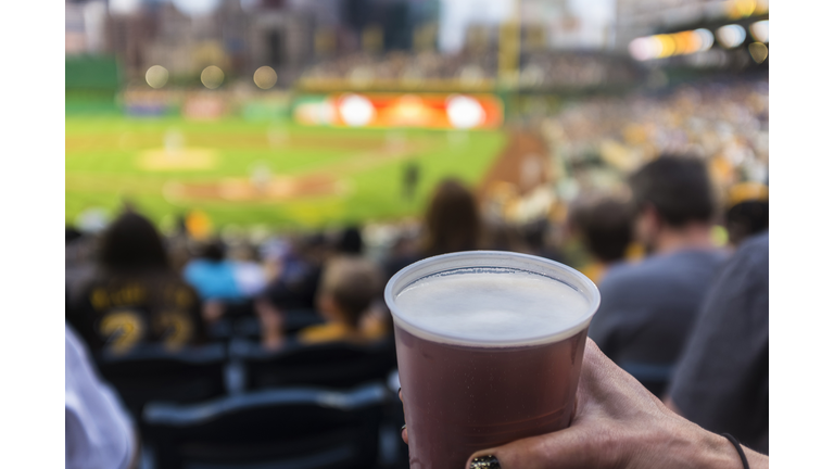 Hand of woman holding cup of beer in baseball stadium