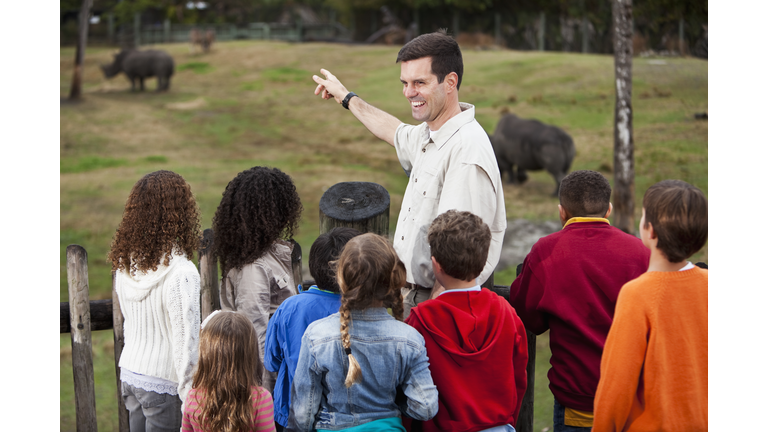 Zoo keeper with group of children at rhino exhibit