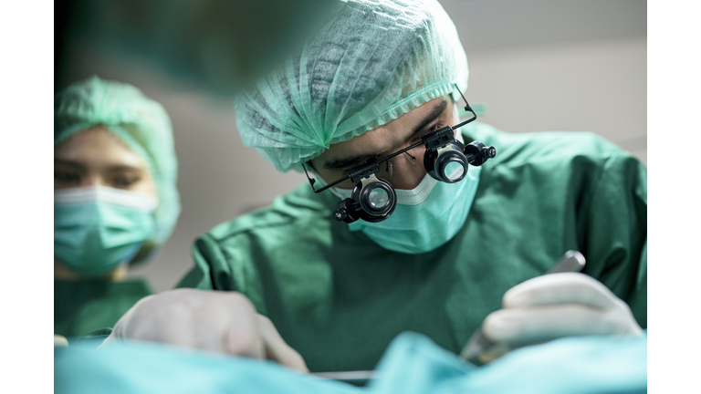 The Business of Plastic surgery. Surgeons operating patient for breast implant in Surgery Clinic.