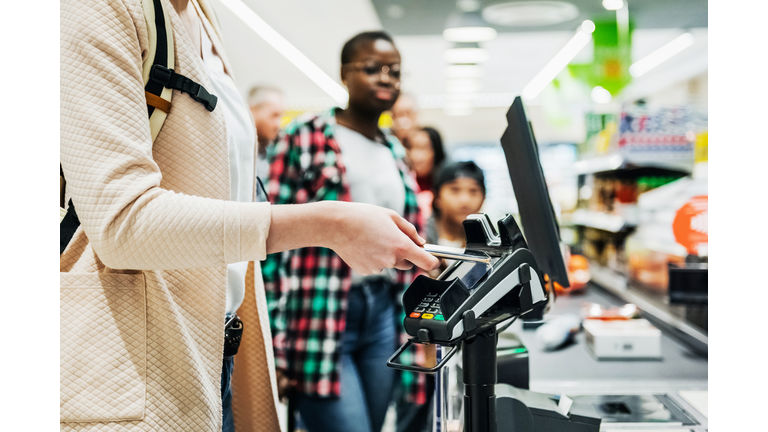 Woman Using Smartphone To Pay For Groceries