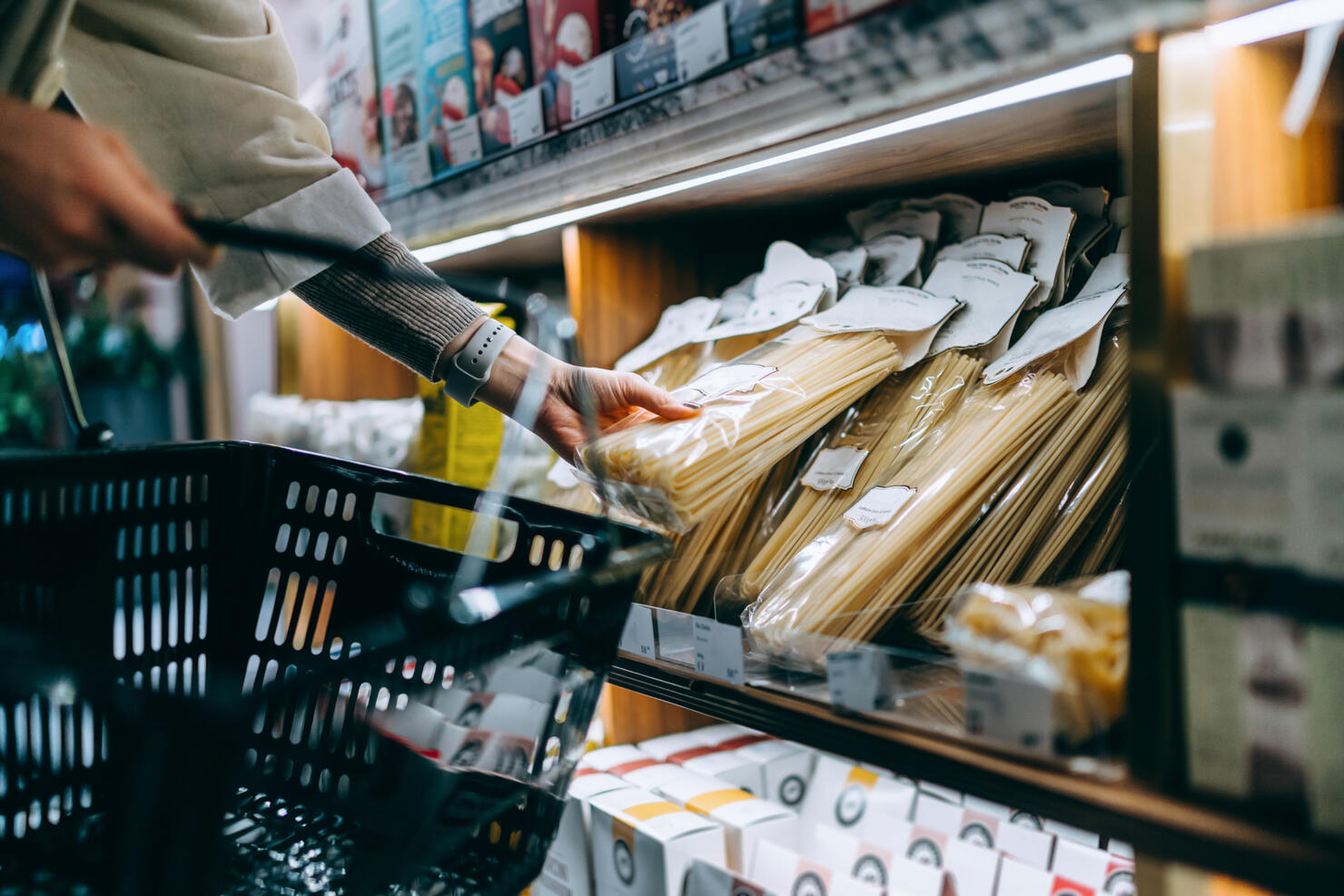Close up of young Asian woman grocery shopping for daily necessities in supermarket, choosing a pack of organic Italian pasta. Healthy eating and home cooking lifestyle