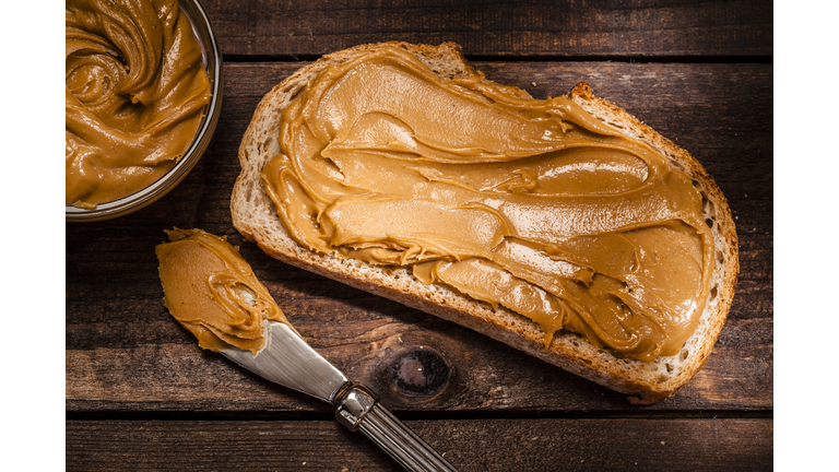 Peanut butter on bread slice shot on rustic wooden table