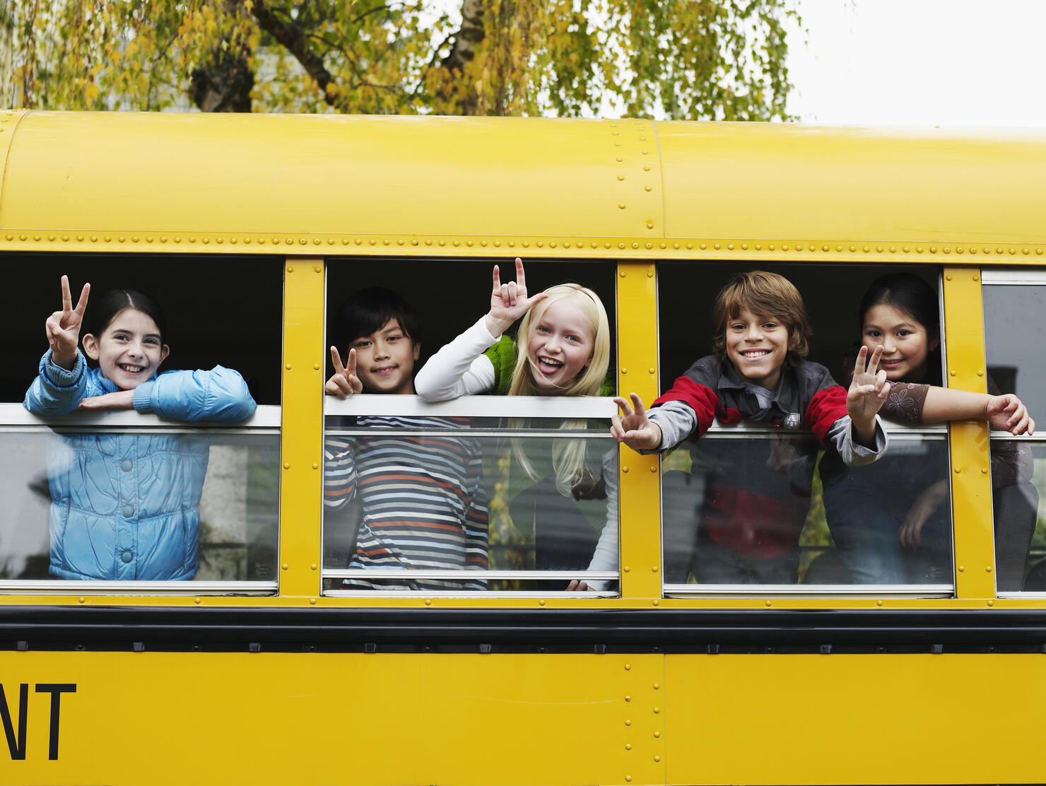 Group of young students hanging out bus windows