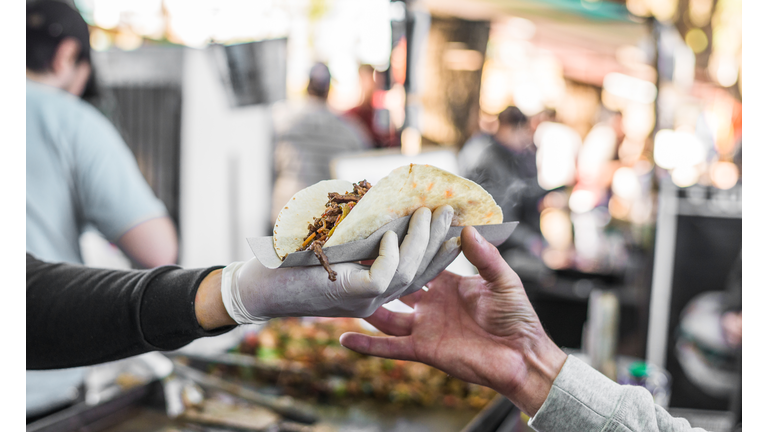 Chef handing a taco to a foodie at a street food market