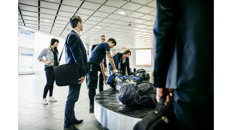 Group of travellers waiting for their luggage at baggage claim