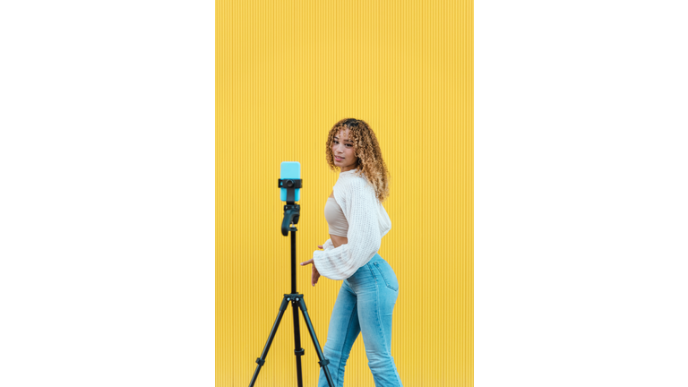 Carefree Hispanic woman recording video on street