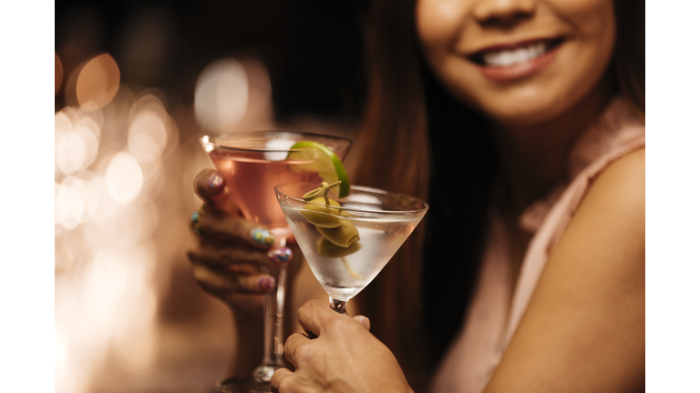 Woman toasting glasses with date at bar