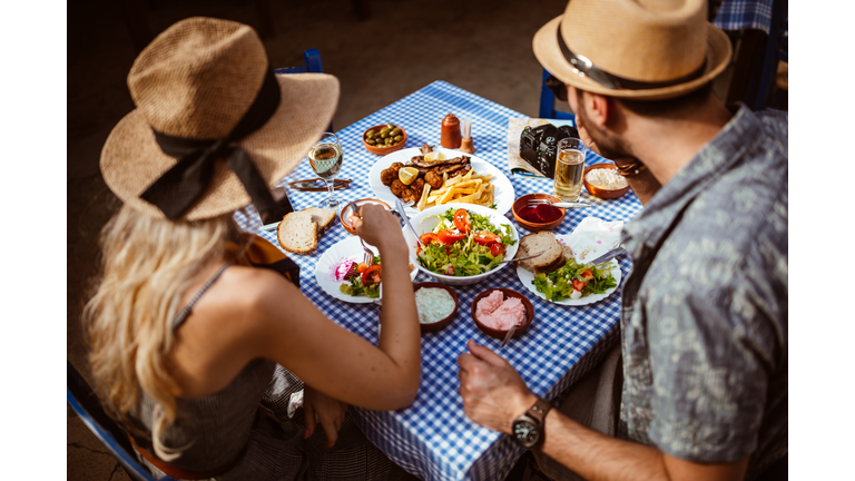 Young tourists couple eating traditional Greek food at rustic restaurant