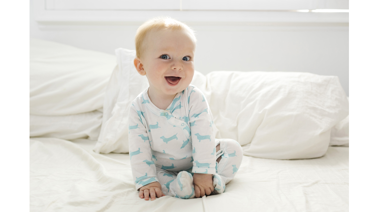 Baby boy (6-11 months) lying on bed