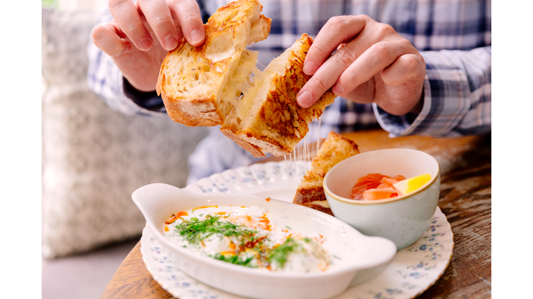 Man eating grilled cheese sandwich in a cafe for breakfast