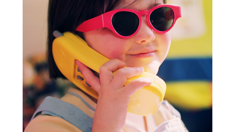 Girl (3-5) wearing red sunglasses, holding toy phone (Enhancement)