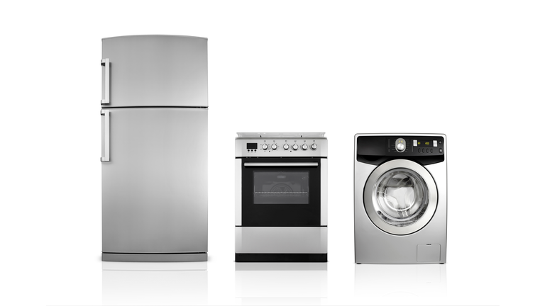 A silver fridge, an oven and dryer lined up side by side