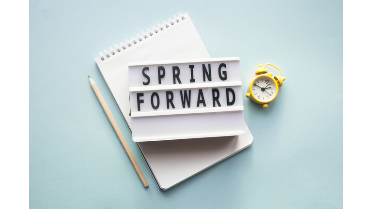 Spring forward concept. Alarm clock, pen and notepad. Daylight saving time.
