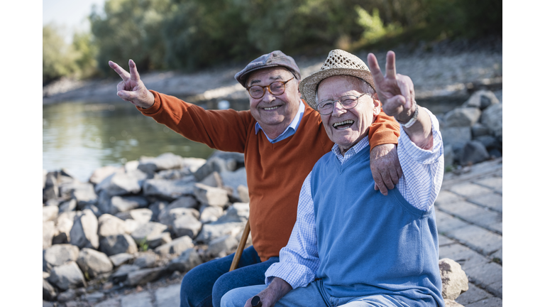 Two old friends sitting by the riverside, having fun