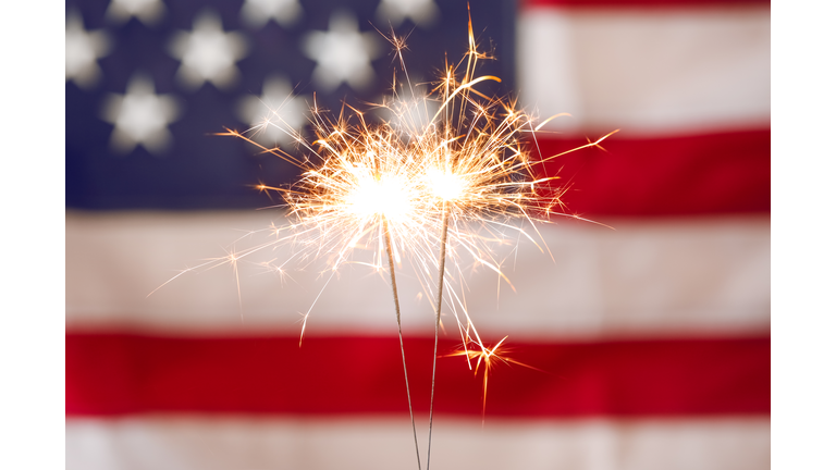 Bright burning sparklers against American flag, closeup