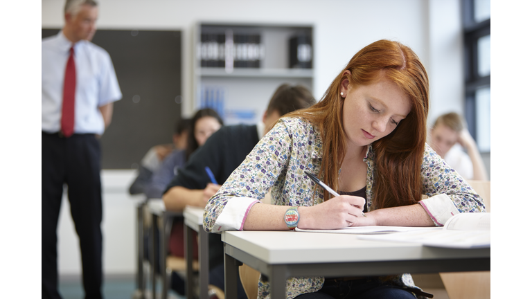 Teacher watching over teenagers in classroom