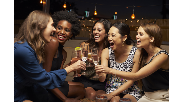 Group Of Female Friends Enjoying Night Out At Rooftop Bar