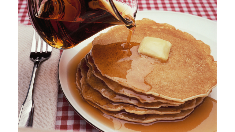 Pouring Maple Syrup on Plate of Pancakes