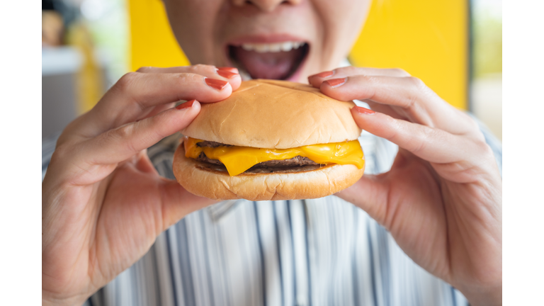 Close up of woman opened her mouth to eat a cheese burger.