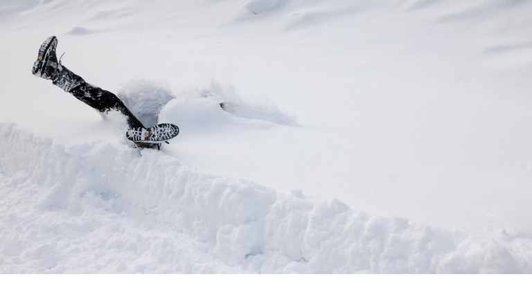 Man is falling headfirst into deep snow. Concept of winterly slippery conditions.