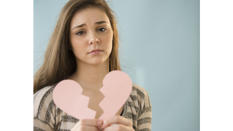 Hispanic girl holding broken heart shape