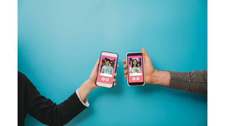Conceptual image of two hands holding smart phones with an online dating app on the screen