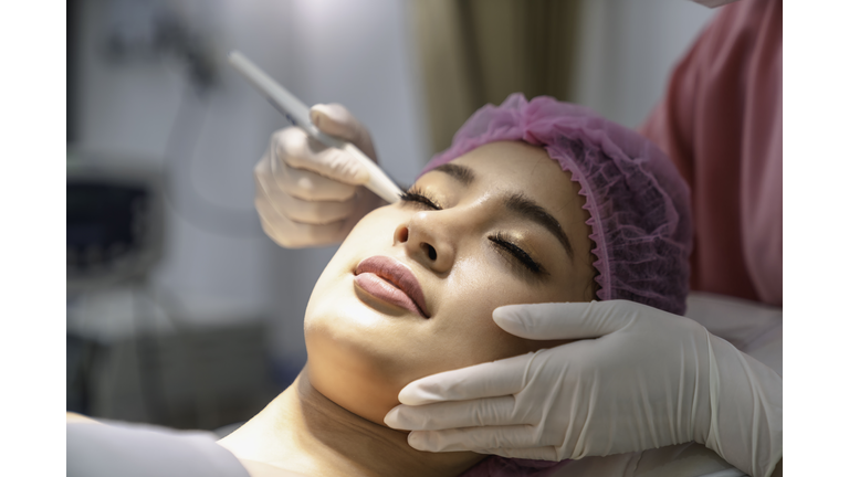 Portrait Of Young Woman with the beauty clinic backgrounds with receiving facial microdermabrasion treatment.