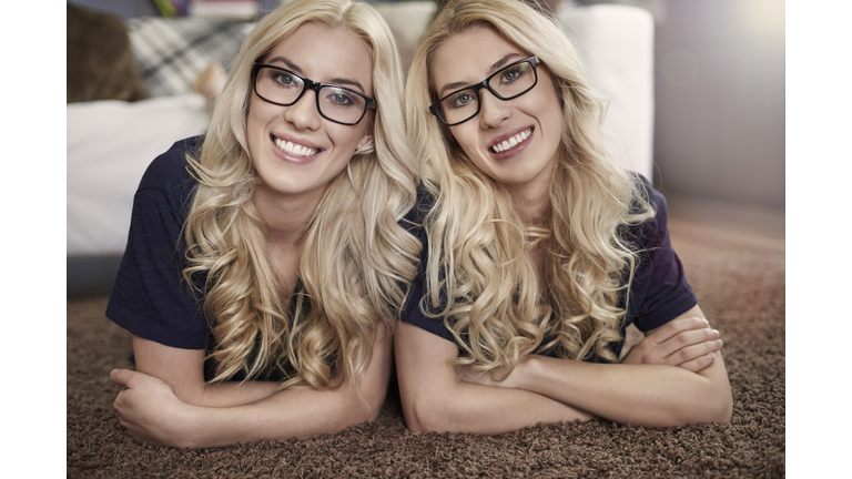 Smiling blonde twins wearing fashion glasses