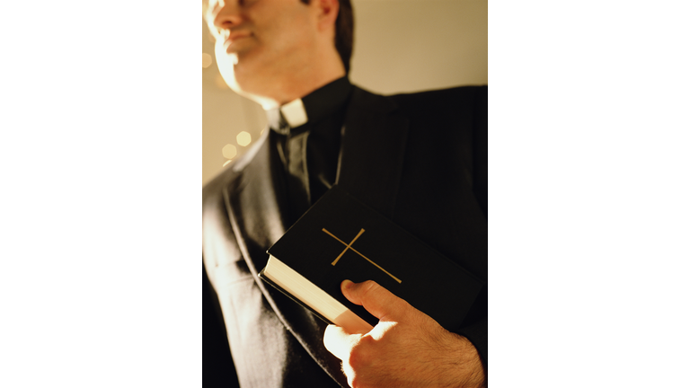 Priest holding bible, close-up, low angle view