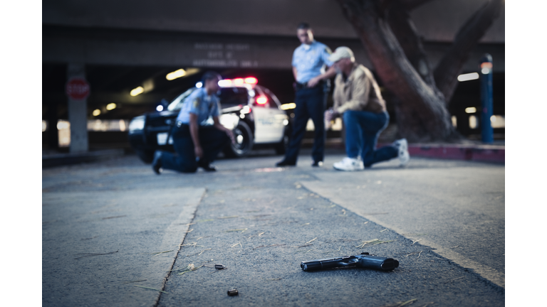 Police examining crime scene with gun on ground