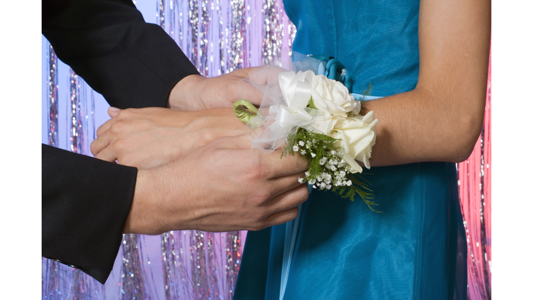 Close-up of boy helping girl with wrist corsage for prom