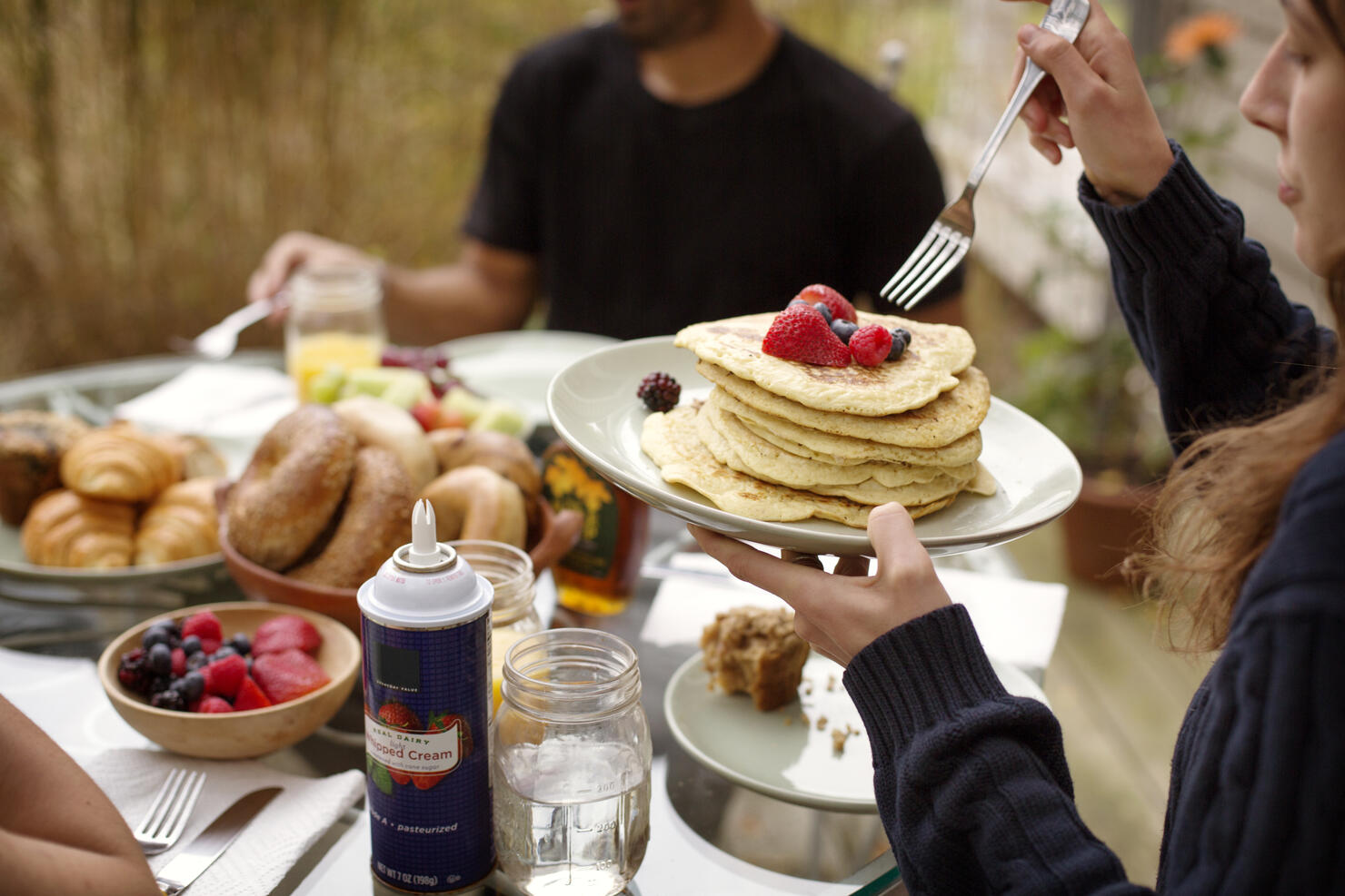 Young woman eating pancakes during breakfast with friends