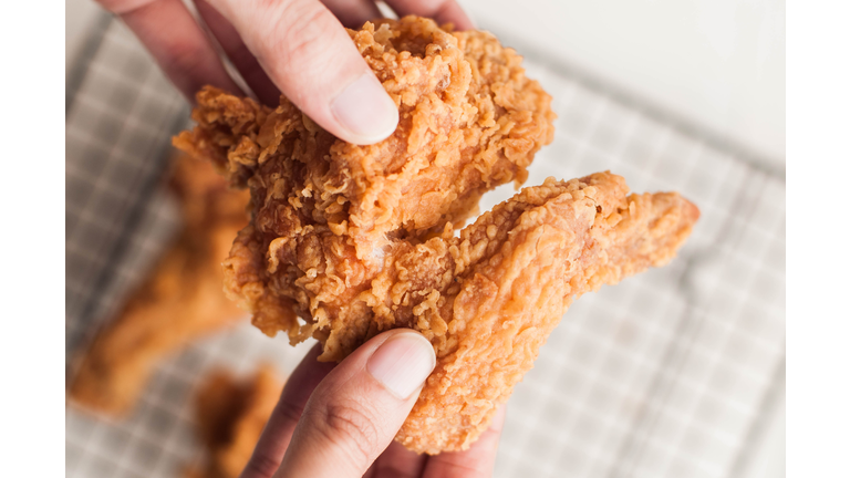 A Southeast Asian person holding fried chicken wings