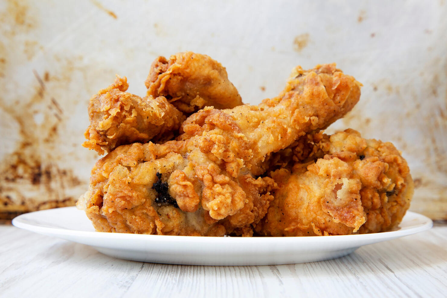 Fried chicken drumsticks on a white round plate, closeup. Side view.