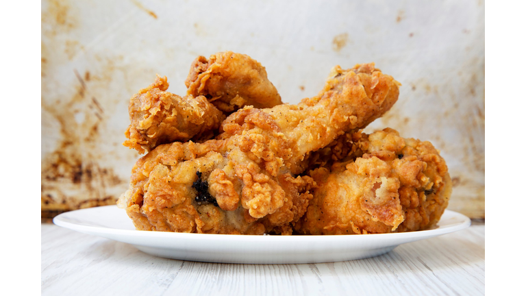 Fried chicken drumsticks on a white round plate, closeup. Side view.