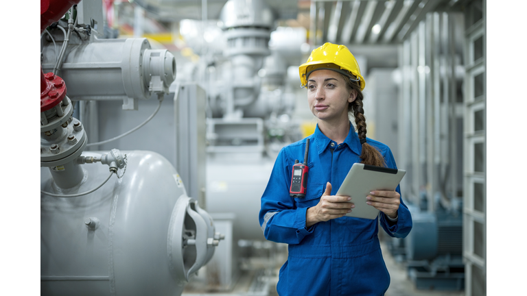 The HVAC ( Heating, Ventilation and Air Conditioning ) control systems.  Female stationary engineer working at industrial mechanical room, examining the operation of the ventilation system in the factory.