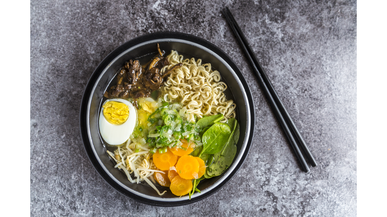 Bowl of ramen soup with spinach, carrot, boiled egg, bamboo sprouts and mushrooms