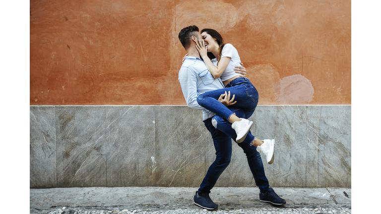 Carefree couple in love in front of a wall outdoors
