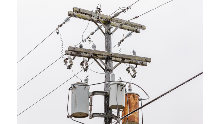 Ice on electrical utility pole and power line from freezing rain. Concept of winter storm and power outage.
