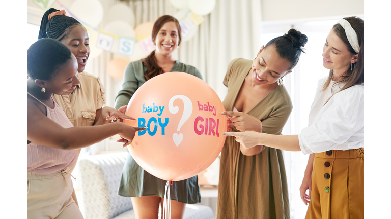 Shot of a group of women about to pop a balloon for a gender reveal during a baby shower