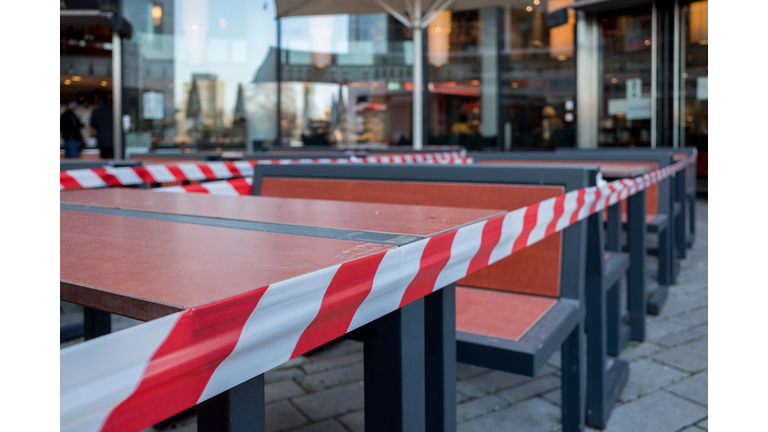 Selected focus view at Red and white caution tape restrict outdoor dining area of restaurant or cafe in Düsseldorf, Germany during lockdown by epidemic COVID-19.