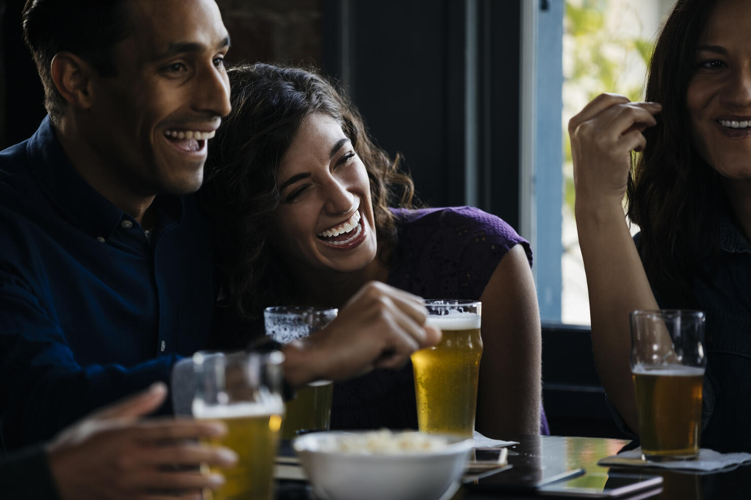 Friends laughing over drinks in bar